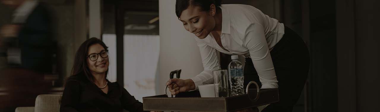 A woman serves drinks to a traveler in the airport lounge