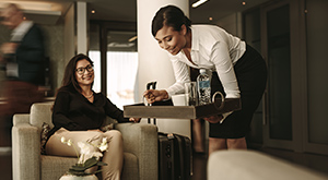 A woman serves drinks to a traveler in the airport lounge