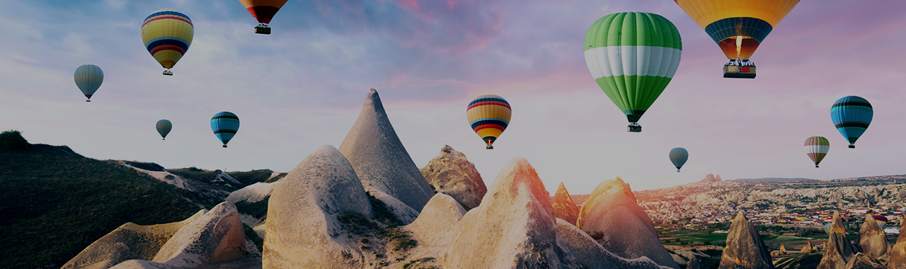 Colorful hot air balloons flying over the volcanic peaks of Göreme National Park in Cappadocia, Anatolia – the heartland of Turkey