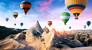 Colorful hot air balloons flying over the volcanic peaks of Göreme National Park in Cappadocia, Anatolia – the heartland of Turkey